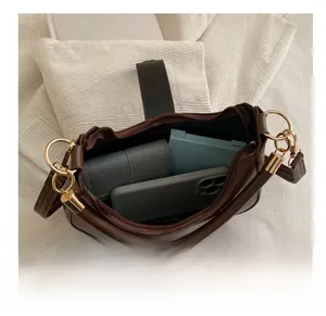 Detail showing spacious interior of dark brown crescent bag with phone and wallet