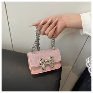 Macro detail of pink glitter mini bag with large silver bow and thick metal chain