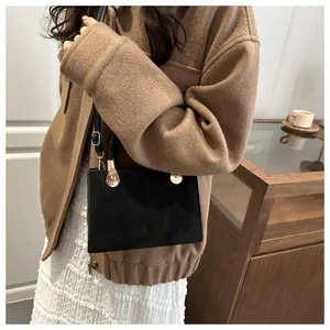 Chic black leather crossbody bag with gold hardware styled with a brown wool jacket
