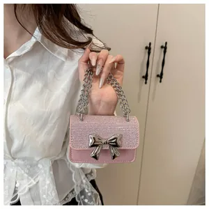 Close-up of pink mini bag with glitter texture flap and silver metal bow clasp