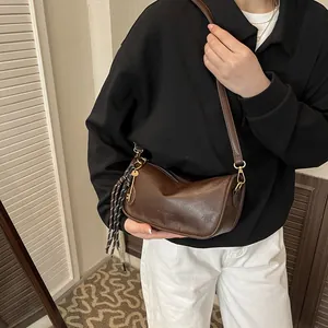 Borsa a spalla a mezzaluna in pelle opaca marrone scuro indossata con outfit casual