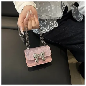 Detail of pink glitter mini bag with silver metal bow and layered chain handle