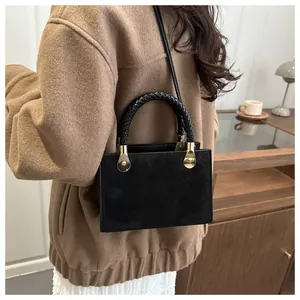 Detail showing vintage black square crossbody bag with textured handle and matte finish