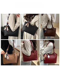 Detail of faux leather tote bag showing silk scarf wrapped handle and metal buckle hardware