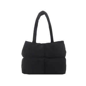 Modern black quilted puffer tote bag with soft padded handles on a white background