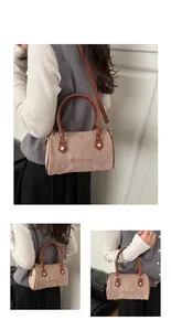 Détail du sac Boston en daim beige avec broderie marron et poignées en cuir élégantes
