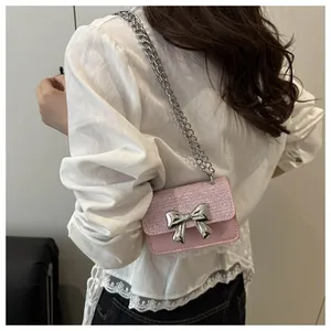 Detail of pink bow handbag featuring sparkling glitter flap and silver metal chain strap