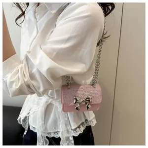 Close-up of pink glitter mini bag with silver bow accent on a model white lace shirt