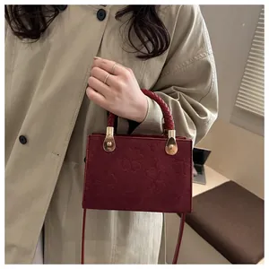 Detail view of vintage burgundy crossbody bag with clover embossing and woven handle