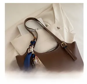 Detail of dark brown tote bag featuring white stitching and silk scarf handle decoration