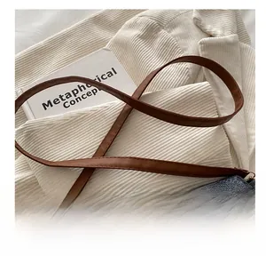 Detail of adjustable brown leather shoulder strap on retro printed crossbody bag