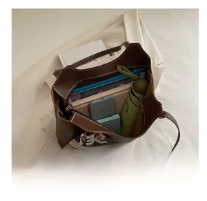 Top view of brown leather tote bag interior with tablet, umbrella and printed silk scarf
