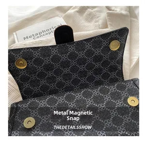 Detail of magnetic gold hardware buckle on clover pattern gray handbag