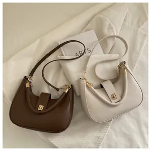 Detail of crescent shoulder bags with gold twist locks in brown and cream colors