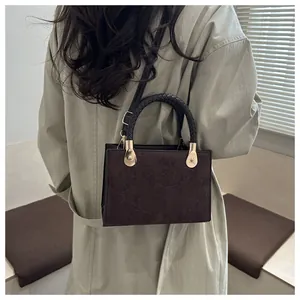 Detailed view of dark brown suede crossbody bag featuring a unique clover embossing pattern