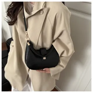 Detail of minimalist black crescent bag featuring golden metallic buckle and smooth leather