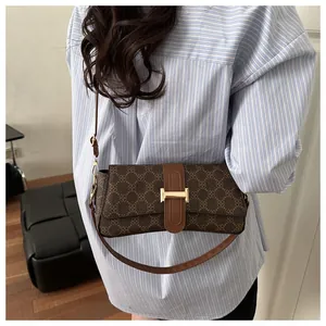 Close-up of vintage brown crossbody bag with geometric pattern and golden H-shaped clasp