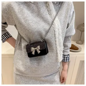 Detailed view of mini black sequin bag with silver bow accent and slim chain strap