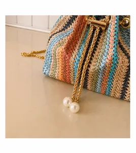 Detail of colorful woven straw bag featuring gold chain drawstring and pearl accents