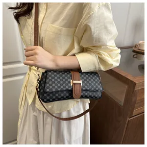 Detail of grey geometric pattern crossbody bag with brown leather strap and gold buckle