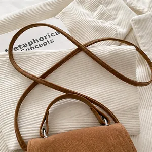 Detail view of brown pebbled leather texture and silver buckle on a stylish crossbody bag