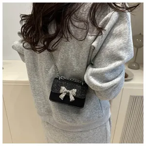 Close-up of black sequined mini crossbody bag with silver bow and metal chain strap
