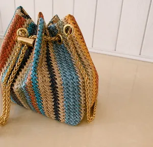 Detail showing the colorful woven texture and gold chain strap of the bucket bag