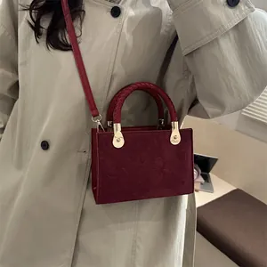 Vintage burgundy crossbody bag with clover pattern and woven handle shown on model