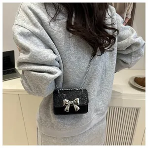 Detail of mini black glitter bag with large silver metal bow and fine chain strap
