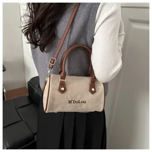 Detail of a beige matte Boston bag with brown handles showing crossbody strap and metal hardware
