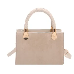 Minimalist beige crossbody square bag with woven handle and gold hardware in plain view