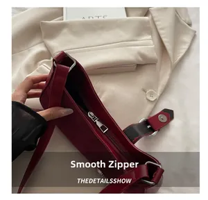 Detail of smooth silver zipper and suede texture on burgundy shoulder bag for women