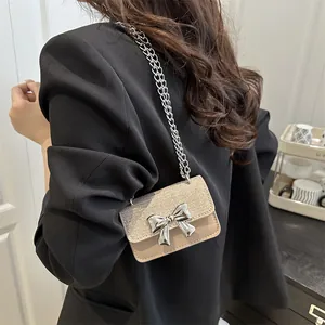 Mini beige leather crossbody bag with glitter flap and silver bow clasp on chain strap