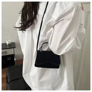 Minimalist black matte crossbody bag shown on model with white shirt for size reference
