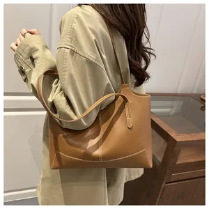 Détail d'un sac cabas en cuir marron avec surpiqûres blanches et fine bandoulière