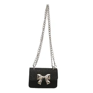 Mini black crossbody bag with silver bow detail and sparkling flap on white background
