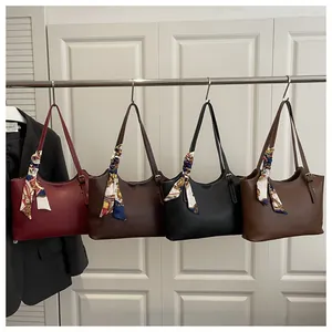 Detail of four colorful tote bags with white stitching and decorative silk scarves on rack