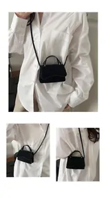 Detail view of mini black suede handbag with thin strap and curved flap design