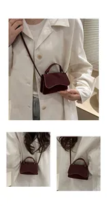 Detail view of burgundy suede mini crossbody bag showing flap closure and curved bottom design