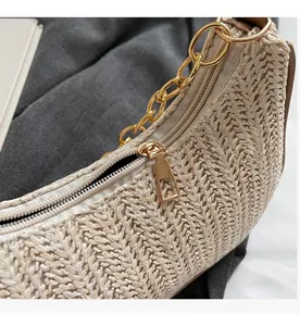 Close-up of woven straw shoulder bag featuring a premium gold zipper and chunky metal chain