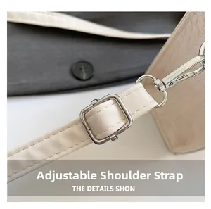 Detail of adjustable shoulder strap with silver buckle on beige crocodile textured handbag