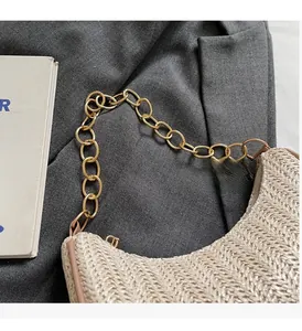Close-up of woven straw crescent bag with a chunky gold chain handle detail
