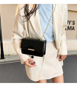 Close-up of black patent leather crossbody bag with gold metal hardware and chain strap