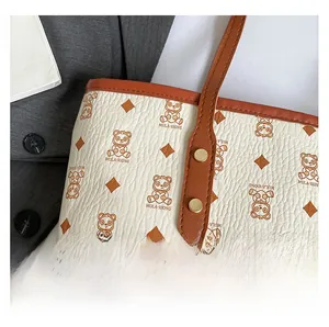 Close-up of pebble-textured tote bag showing brown bear prints and gold rivet details