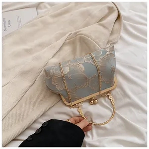 Detail der hellblauen Qipao-Handtasche mit Blumenstickerei und goldenem Metallringgriff