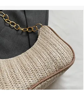 Detail of woven straw handbag featuring golden chain strap and herringbone texture