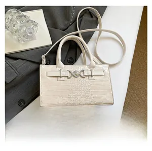 Macro detail of creamy white crocodile embossed leather bag with heart-shaped silver buckle
