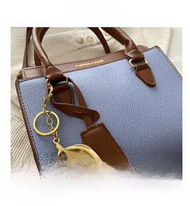 Détail du sac à main en cuir bleu clair avec garniture brune et breloque cerise