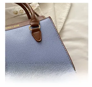 Détail du sac cabas en cuir bleu et marron avec anneau métallique doré et lettrage