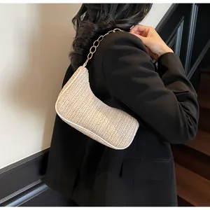 Detailed texture of beige woven straw shoulder bag featuring a chunky gold chain strap